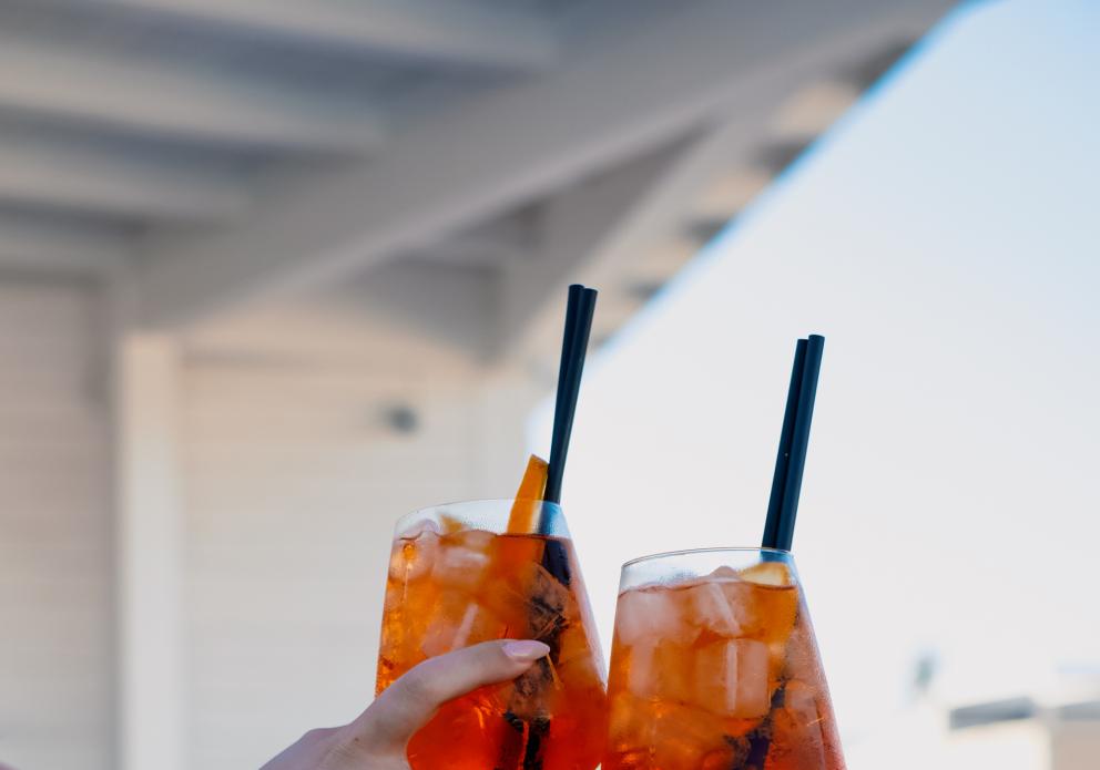 Due calici brindano al tramonto, spritz e gioia condivisa.