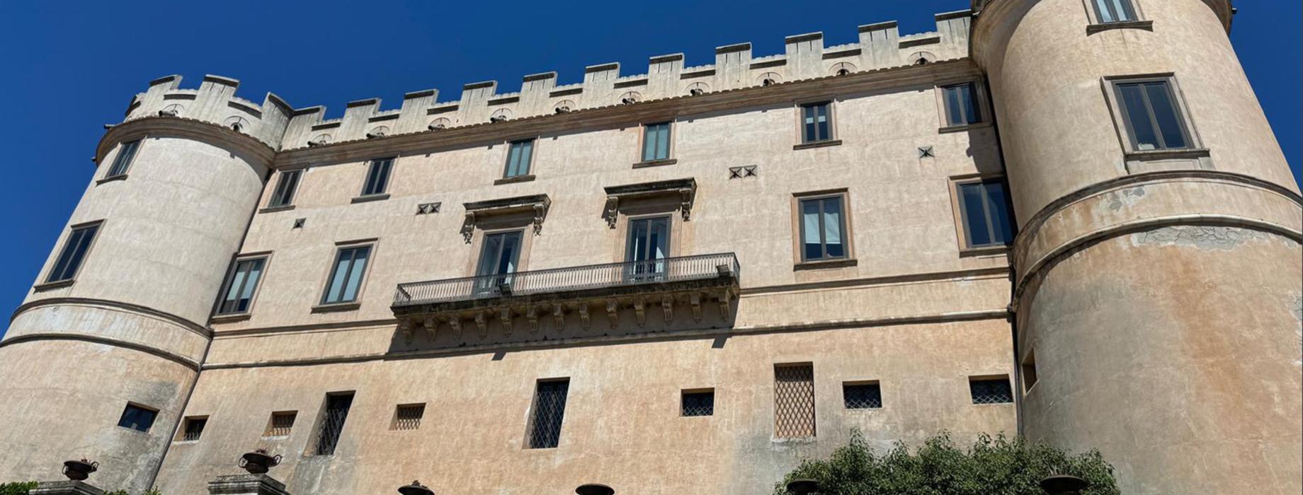 Donna con cappello ammira un borgo costiero arroccato su una scogliera.