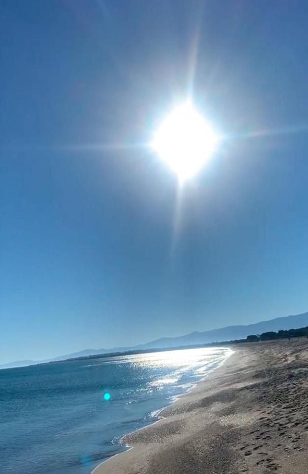 Spiaggia affollata con ombrelloni colorati e mare cristallino, vista dall'alto.